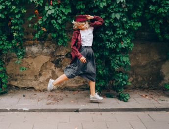 ragazza che corre spensierata sul marciapiede